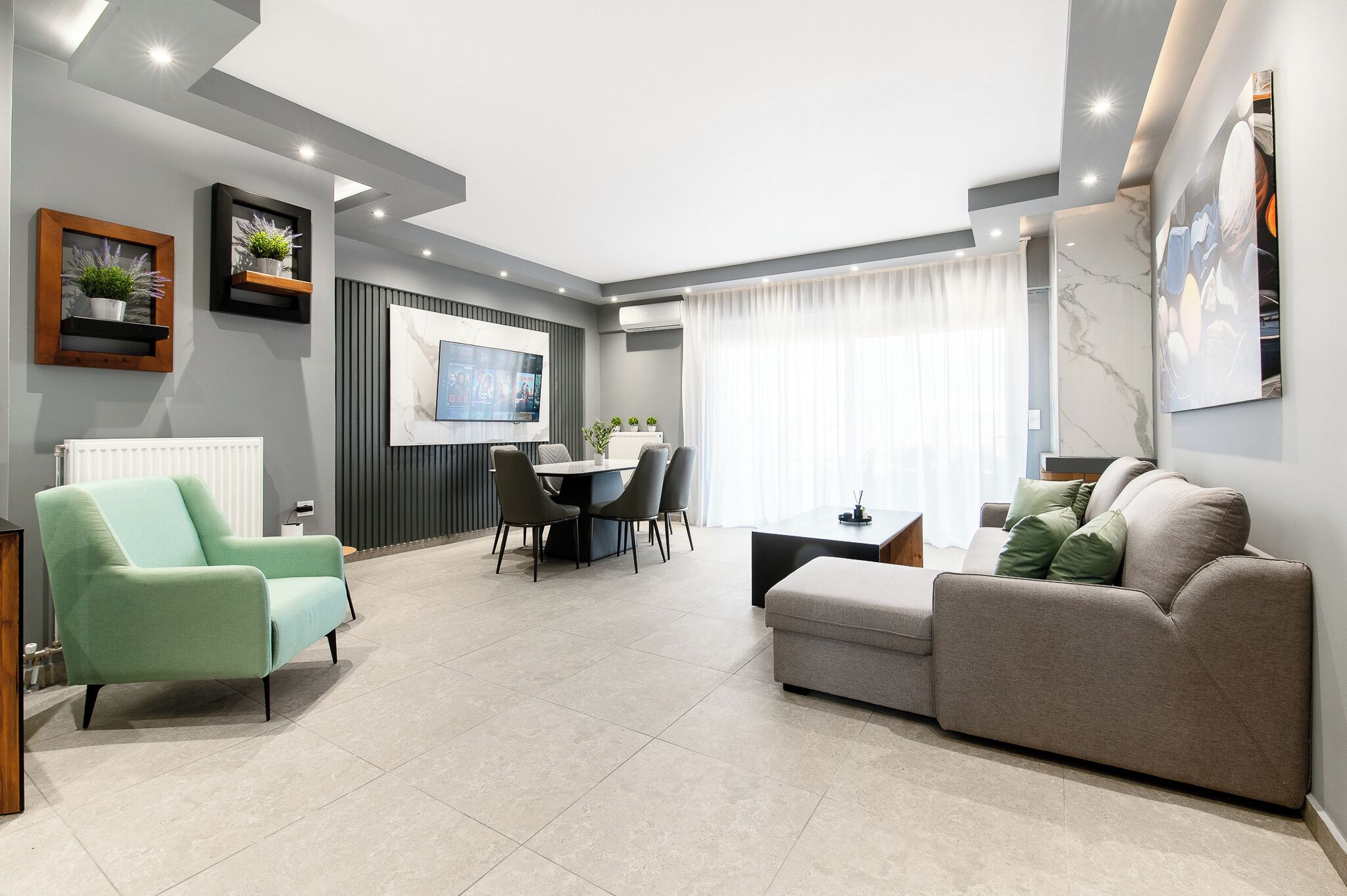 Uma sala de estar moderna com sofá, poltrona, mesa de jantar e televisão.