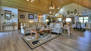 A spacious living room with a high ceiling, wooden floors, and a central coffee table. - Pet-friendly, family-sized luxury cabin rental, hot tub, WiFi, firepit (Mineral Bluff)