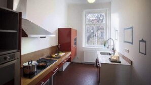 A compact kitchen with a stove, sink, and window. - Waterfront Apt w/ River Views & Trendy Location (Praha 5)
