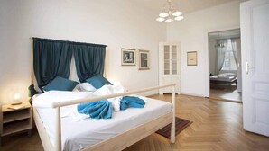 A bedroom with a bed, curtains, a nightstand, a cabinet, and a door leading to another room. - Waterfront Apt w/ River Views & Trendy Location (Praha 5)