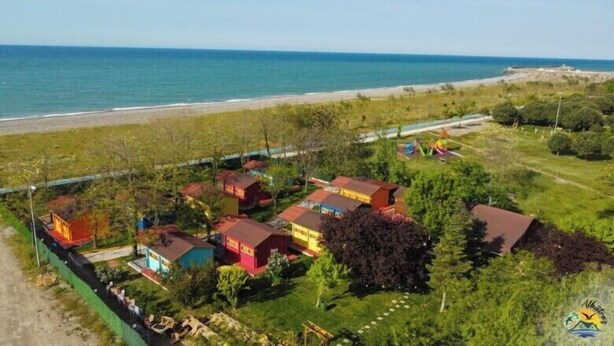 Luchtbeeld van een kustgebied met kleurrijke huizen, een strand en een heldere lucht.