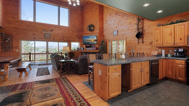 A spacious kitchen with wooden cabinets, a large island, and a dining area with a view of the mountains.