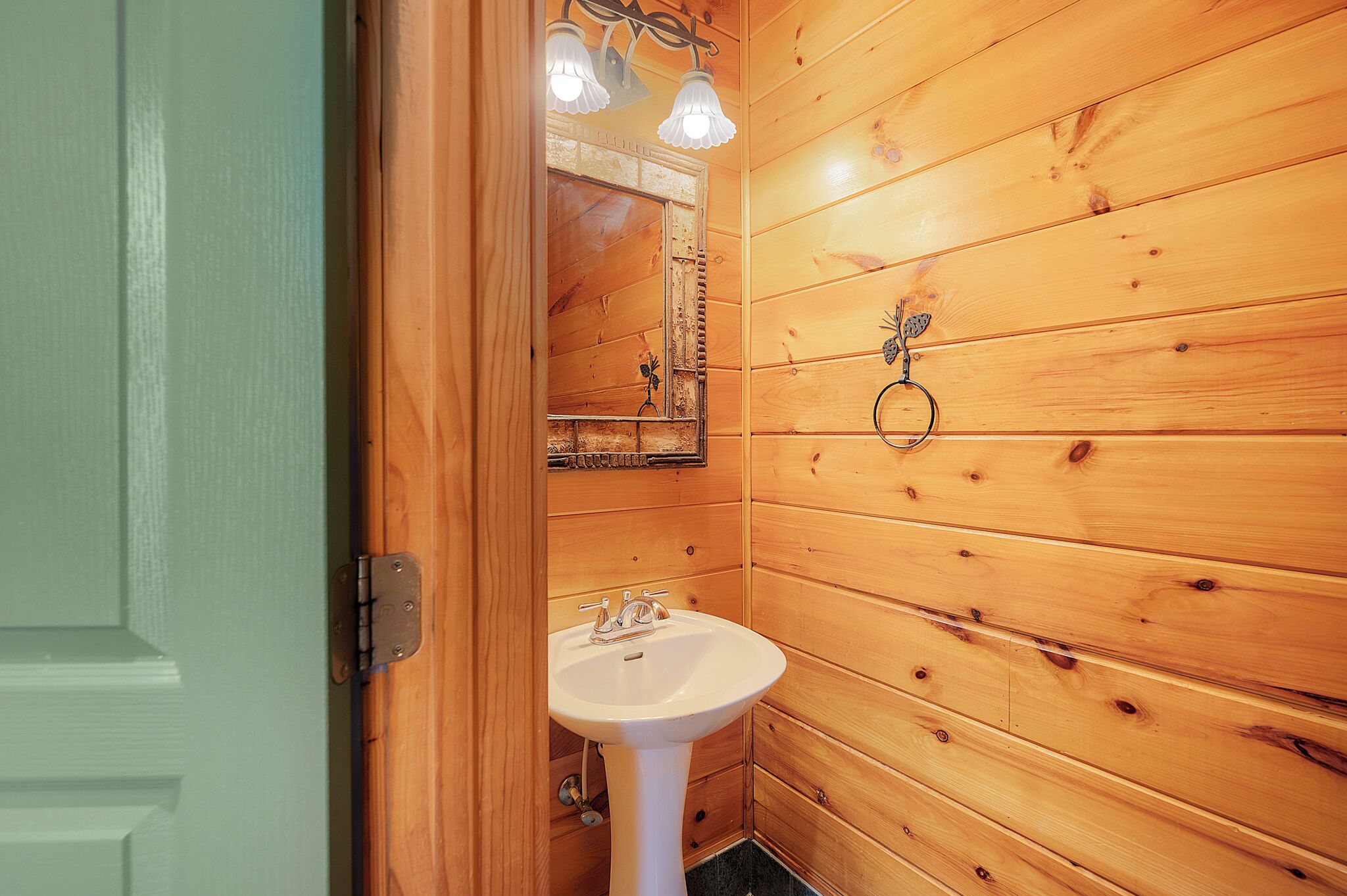 A wooden-paneled bathroom with a white sink and a mirror above it.