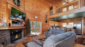 A spacious living room with a fireplace, a large flat-screen TV, and a cozy seating area.