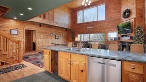 A spacious kitchen with wooden cabinets, a stainless steel dishwasher, and a large window.