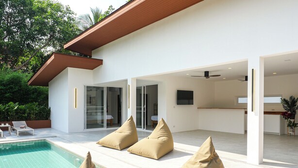 Une maison moderne dotée d’une piscine, d’un espace extérieur aménagé et d’un coin cuisine.