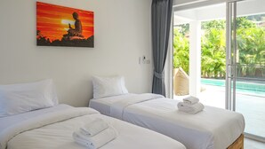Une chambre d’hôtel avec deux lits, un tableau représentant un Bouddha et une vue sur une piscine.