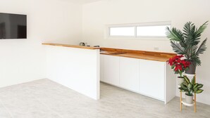 Une cuisine moderne avec un plan de travail en bois, des armoires blanches, un ventilateur de plafond et une fenêtre.