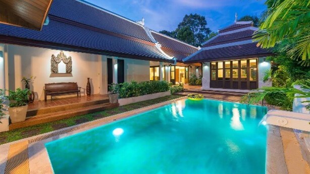 A swimming pool with a wooden deck and a bench, surrounded by lush greenery and traditional architecture. - Balinese-inspired 3-bedroom villa with private pool, garden, and 5-min walk to Bang Kao Beach (Koh Samui)