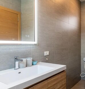 A modern bathroom with a large mirror, a white sink, and grey tiles. - Villa Blue Bird, 2-bedroom retreat, private pool, mountain views, modern comfort (Tambon Maret)