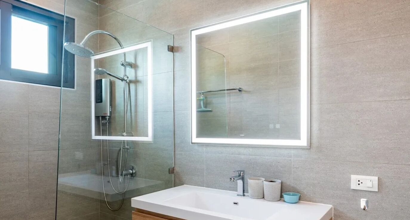Une salle de bain moderne avec une douche à parois de verre, un grand miroir et un lavabo blanc.