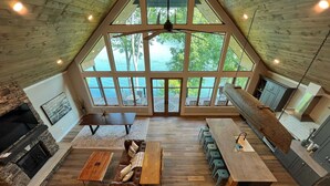 Amplio espacio tipo loft con cocina integrada, suelos de madera y vistas a un lago a través de grandes ventanales.