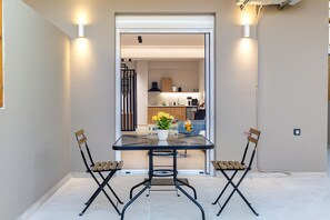 A dining area with a table and two chairs, a potted plant, and a view into a kitchen. - Dom Azure Elegant Studios (Chania)