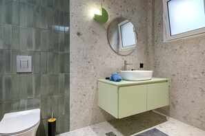 A modern bathroom with a white toilet, a green vanity with a white sink, and a mirror above the sink. - Dom Azure Elegant Studios (Chania)