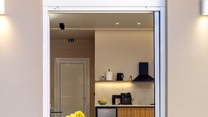 A compact living space with a kitchenette, a dining area with a table and chairs, and a small seating area with a sofa and cushions. - Dom Azure Elegant Studios (Chania)