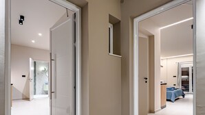 A modern hotel hallway with two doors leading to rooms, a small window, and a bathroom visible in the background. - Dom Azure Elegant Studios (Chania)