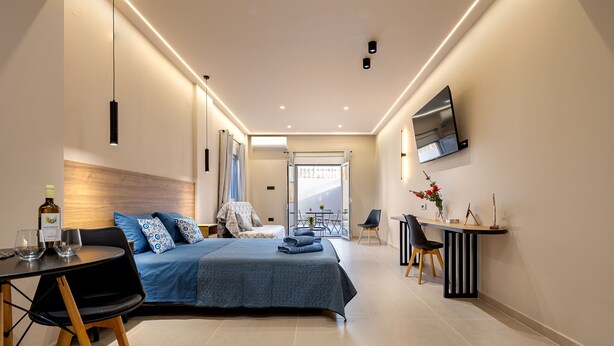 A modern hotel room with a bed, a desk, and a TV. - Dom Azure Elegant Studios (Chania)