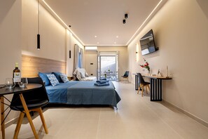 Moderni hotellihuone, jossa on sänky, työpöytä ja televisio.