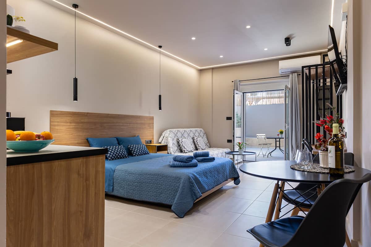 A modern bedroom with a bed, bedside table, and a dining area with a table and chairs.