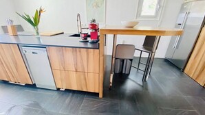 A modern kitchen with a wooden countertop, a dishwasher, a coffee maker, and a small table with a chair. - Intimate Family Villa with big private pool & panoramic sea view (CT)