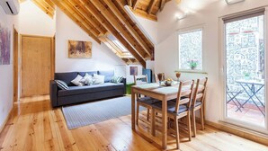 A cozy room with a wooden ceiling, a sofa, a dining table with chairs, and a window with a view of a tiled area. - Wooden Top With Terrace (Lisbon)
