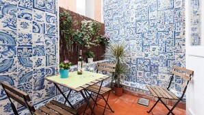 A patio with blue and white patterned tiles, wooden furniture, and potted plants. - Wooden Top With Terrace (Lisbon)