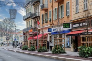 A street with buildings, outdoor seating, and a sign for 'MARKET DU PORT'.