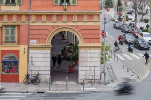 Vista de la calle con la entrada de un edificio, una bicicleta y coches aparcados.