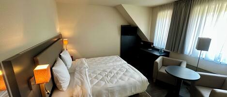 Una habitación de hotel con cama, escritorio, silla y una mesita.
