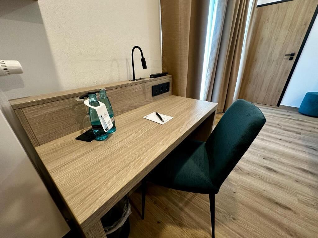 A wooden desk with a chair, a bottle of water, and a notepad.