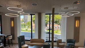 A modern interior with a seating area, large windows, and a ceiling with circular light fixtures.