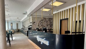 A modern reception area with a curved black counter, wooden flooring, and a map mural on the wall.