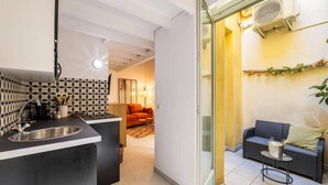 A modern kitchen with a sink, a dining area with a table and chairs, and a living room with a sofa and a plant. - Nice duplex with patio (Niza)