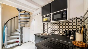 A kitchen with a black stove, a microwave, a sink, and a patterned backsplash. - Nice duplex with patio (Niza)