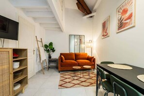 A living room with a sofa, a dining table, a TV, and a mirror. - Nice duplex with patio (Niza)