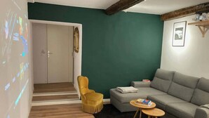 Un salon comprenant un canapé, un fauteuil jaune, une table basse et un écran de projection sur lequel est diffusé un film.