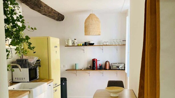 Une cuisine compacte avec un plancher en bois, un coin repas comprenant une table et des chaises, et un luminaire suspendu.