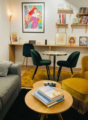 A living room with a sofa, two chairs, a coffee table with books, a painting on the wall, and a bookshelf. - Cozy apartment in the old town – Garibaldi (Niza)
