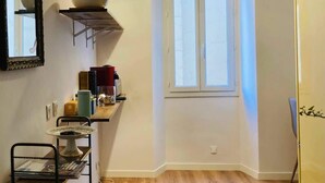 Un espace de vie compact comprenant un coin cuisine, un espace repas et une fenêtre laissant entrer la lumière naturelle.