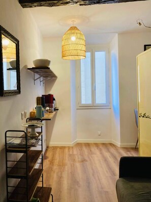 Ein kompakter Wohnraum mit KĂŒchenzeile, Essbereich und einem Fenster fĂŒr natĂŒrliches Licht.