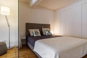 A bedroom with a bed, bedside table, lamp, and a wardrobe. - Beautiful loft between Old Nice and the port (Niza)
