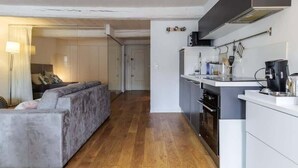 Un espacio habitable pequeño con sofá, kitchenette y una puerta que da a otra habitación.
