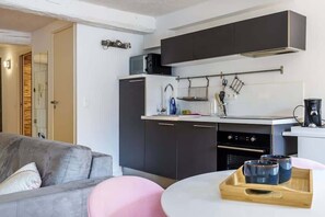 Cocina compacta con armarios oscuros, un microondas y una cafetera.