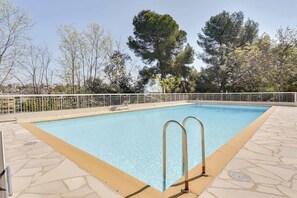 A rectangular swimming pool with two metal ladders on one side, surrounded by a white metal fence.