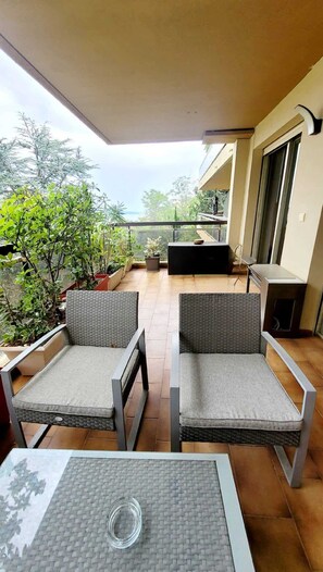 A balcony with two wicker chairs, a small table, and a potted plant.