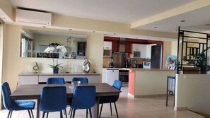 A modern kitchen with a dining area, a staircase, and a living space.
