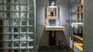 A bathroom with a glass partition, a sink, a mirror, and a towel rack. - Cosy studio place du pin (Niza)