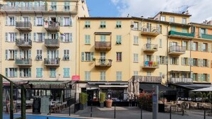 A multi-story building with balconies, a restaurant named 'POSTO 17,' outdoor seating, and a pool area. - Cosy studio place du pin (Niza)