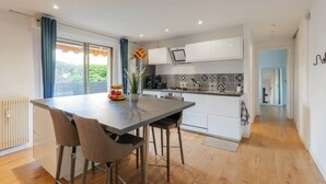 A modern kitchen with a dining area, white cabinets, a tiled backsplash, and a view through the window. - Comfortable Apartment with large sunny terrace (Niza)