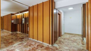 A hallway with wooden paneling, a marble floor, and a door with a sign. - Comfortable Apartment with large sunny terrace (Niza)